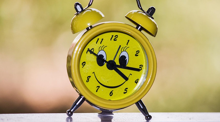 gelber Wecker mit lachendem Gesicht